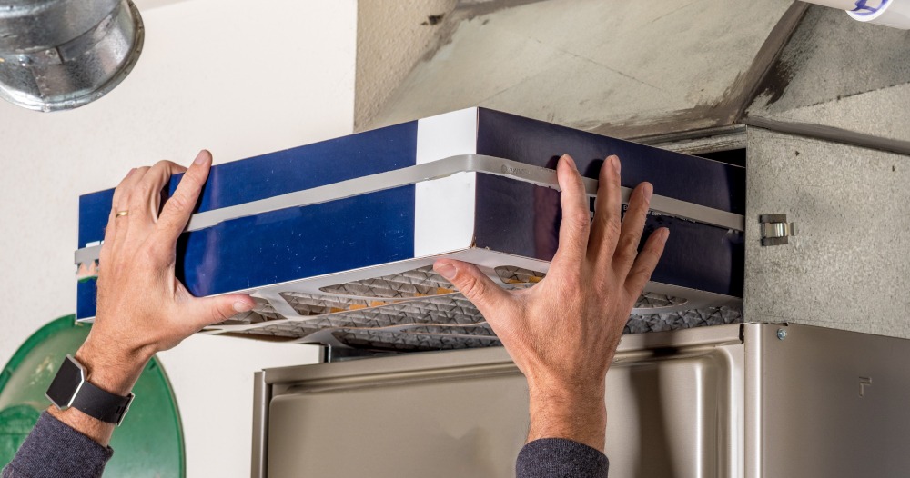 A homeowner inserts a new four-inch filter into his HVAC system.