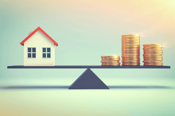 A house on a scale with stacks of coins on top of it